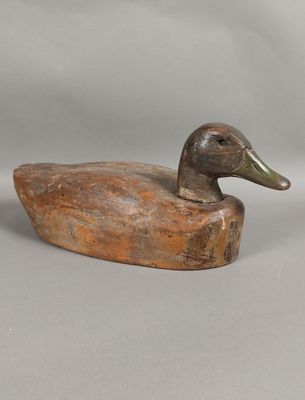 carved wooden duck sitting on a piece of wood with a gray background