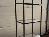a metal shelf with glass shelves on it in a garage