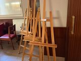 a easel in the middle of a room with chairs and a table