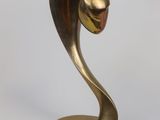 brass sculpture of a bird on a stand against a white background