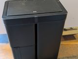 a black trash can sitting on the floor next to a white wall