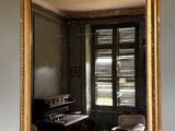 un miroir accroché au mur dans lequel se reflète une pièce où se trouve un piano