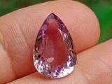 une personne tient un diamant rose dans la main, sur un fond vert