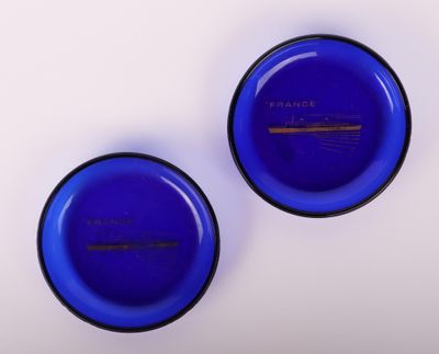 paire de bols en verre bleu avec des bords noirs sur une surface blanche