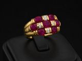 a gold ring with ruby and diamonds on a black surface