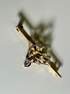a gold brooch with a flower on it on a white surface