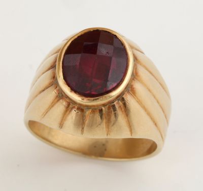 une bague en or avec une pierre rouge au centre
