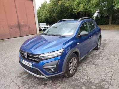 La voiture bleue est garée sur le parking, à côté d'un immeuble.