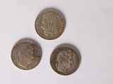 three coins are shown on a white surface with a white background
