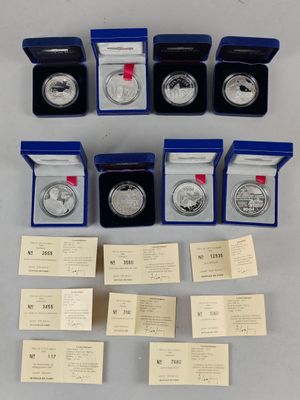 un lot de pièces d'argent rangées dans des boîtes et des pochettes, posées sur une table