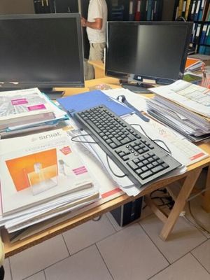 un homme debout devant un bureau équipé de deux écrans et d'un clavier