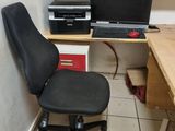 a desk with a computer and a chair in the corner
