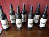 six bottles of wine are lined up on a wooden table