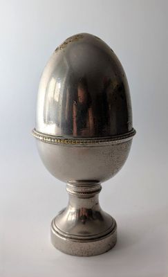une image représentant un œuf en argent posé sur un socle en métal