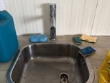 a sink that has a lot of cleaning supplies on the counter