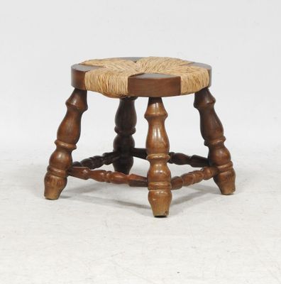 an old wooden stool with a roped seat on top of it