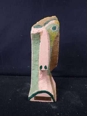 une image représentant une sculpture en bois représentant le visage d'une femme sur une surface noire