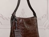 a brown purse sitting on top of a wooden table next to a wall