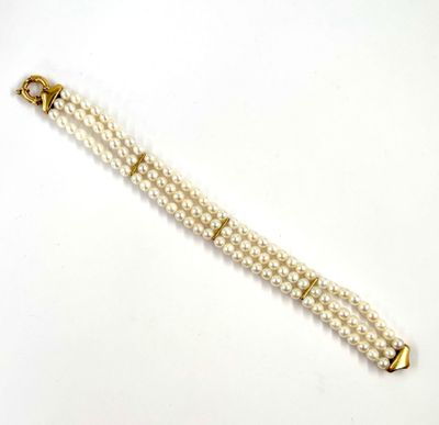 un gros plan sur un bracelet de perles blanches muni d'un fermoir en or