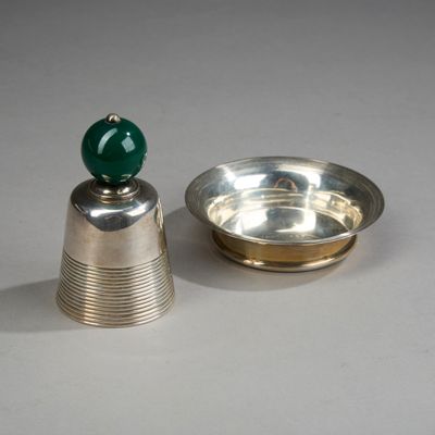 un plateau en argent surmonté d'une perle verte, à côté d'un bol en argent