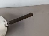 a metal pan with a wooden handle sitting on a table