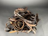 a pile of old leather belts on a gray surface