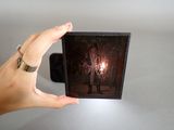 a hand holding a picture of a man holding a candle