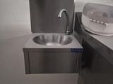 a sink and a soap dispenser in a public bathroom