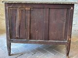 a wooden cabinet with a marble top on a brick floor