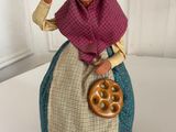 figurine of a woman with a basket of pretzels on a table