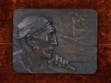 a bronze plaque of a baseball player on a wooden surface