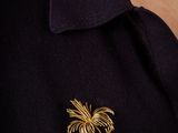 a close up of a person wearing a black shirt and a gold broochet