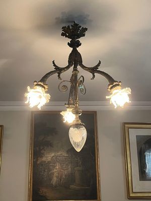 un lustre dans une pièce où sont accrochés des tableaux aux murs