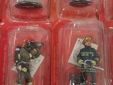six small figurines of firemen in plastic cases