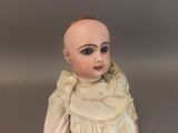 a doll that is wearing a white dress and a scarf