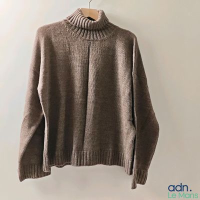 the sweater is hanging on a hanger on the wall