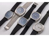 four different types of watches are lined up on a white surface