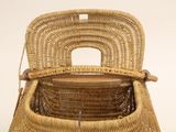 a wicker basket with a wooden handle on a table