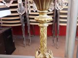 a gold clock on a stand in a room