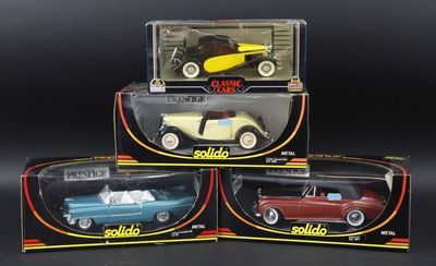 three boxed toy cars are sitting in a box on a black surface