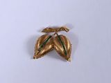 une broche en or ornée d'une feuille verte
