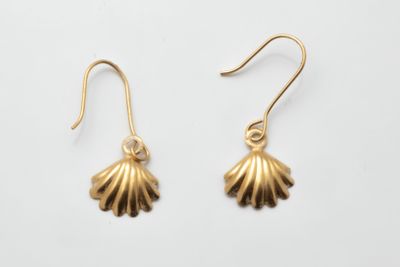 a pair of gold seashell earrings on a white background