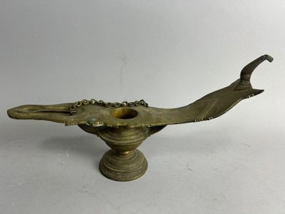 une vieille lampe à huile en laiton surmontée d'un oiseau