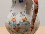 a small vase with a handle sitting on a table