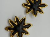 two black and gold flower brooches on a white surface