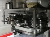pots and pans are stacked on top of a metal shelf in a kitchen