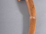 an old wooden object with a curved handle on a gray surface