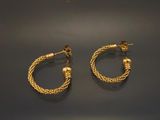 deux paires de boucles d'oreilles créoles en or posées sur une surface noire