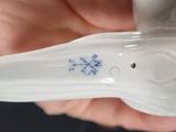 a person holding a white porcelain object with a blue snowflake on it