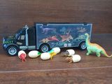 a toy truck with dinosaurs and eggs in front of it